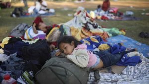 Nayeli Zelaya from El Salvador, rests alongside her two sleeping siblings, at the sports club where Central American migrants traveling with the annual "Stations of the Cross" caravan are camped out, in Matias Romero, Oaxaca State, Mexico, Wednesday, April 4, 2018. The children's father Elmer Zelaya said the family is awaiting temporary transit visas that would allow them to continue to the U.S. border, where they hope to request asylum and join relatives in New York. (AP Photo/Felix Marquez)